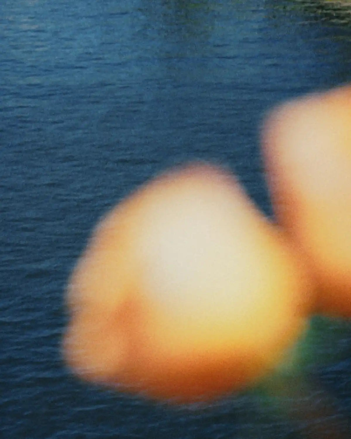 Two out-of-focus, light-colored objects with a warm glow over a body of water.