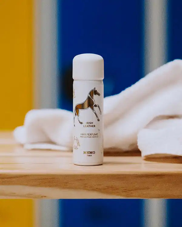 A white spray bottle of ’Irish Leather’ hair perfume with a gold horse illustration.