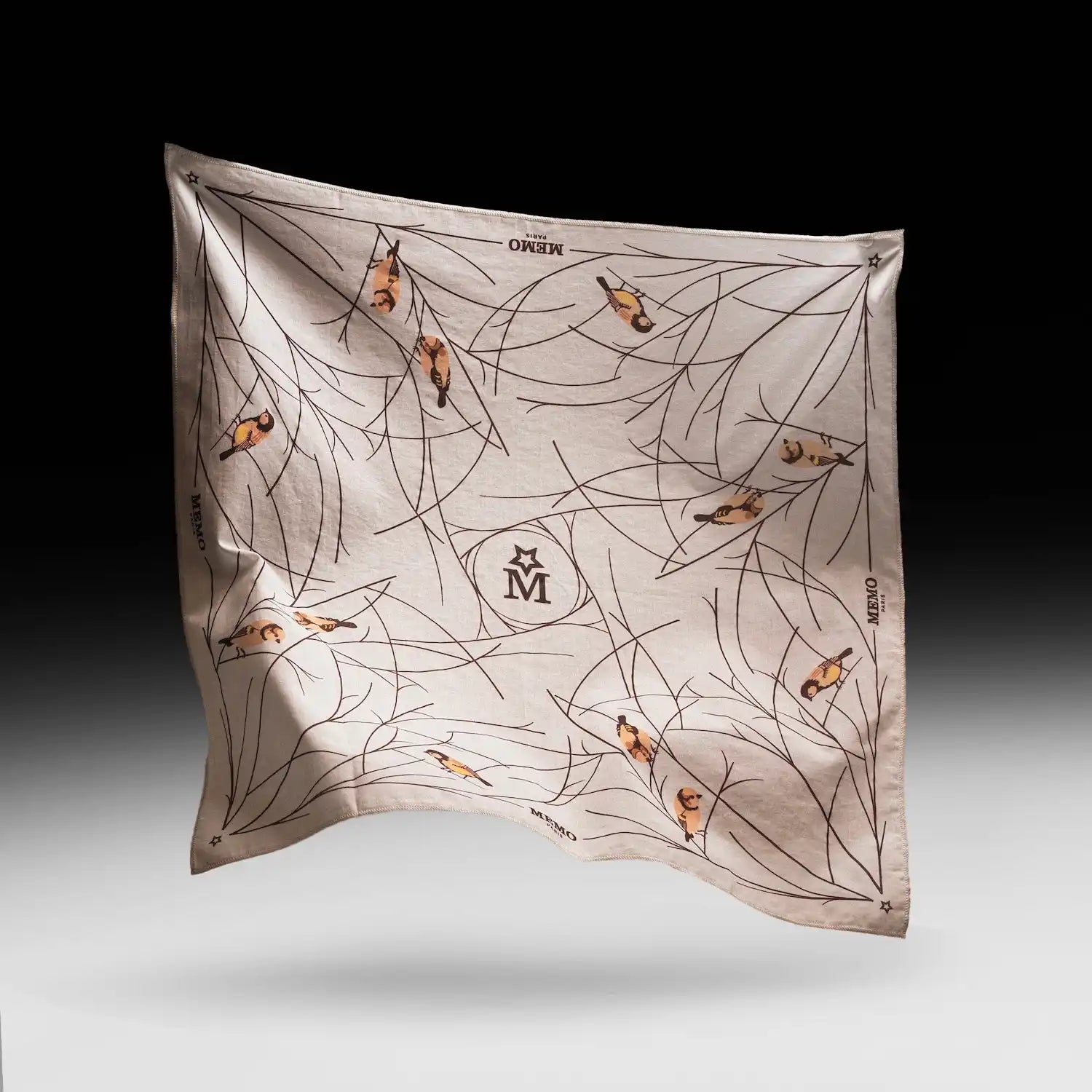 A light-colored silk scarf with a pattern of black branches and small, brown and yellow birds.