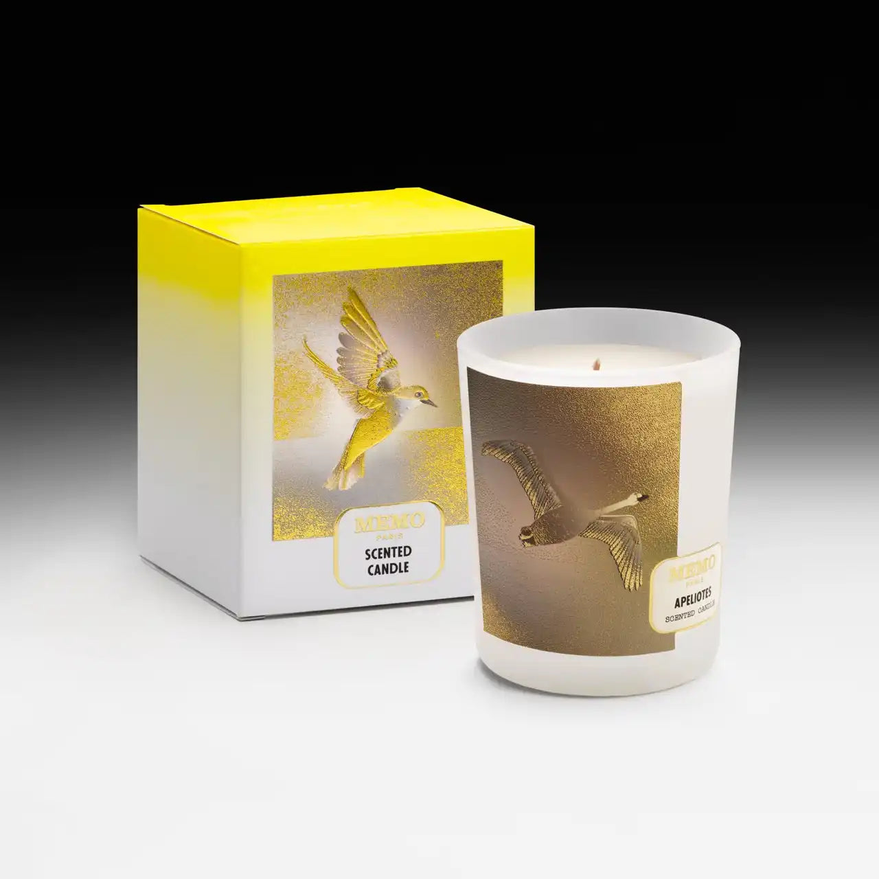 A white scented candle in a glass jar with a gold and white bird design, accompanied by its matching decorative box.